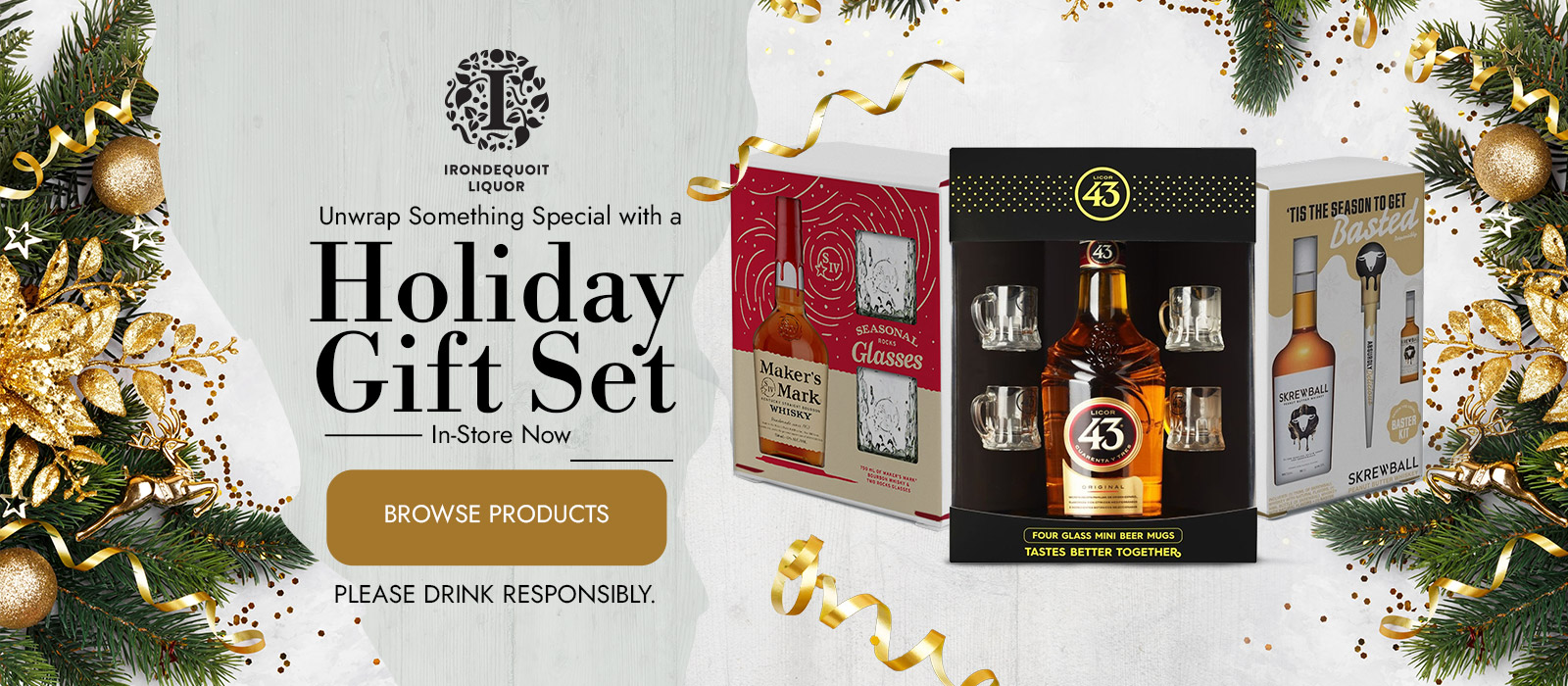 Holiday gift sets with liquor bottles and glasses, surrounded by festive pine and gold décor.