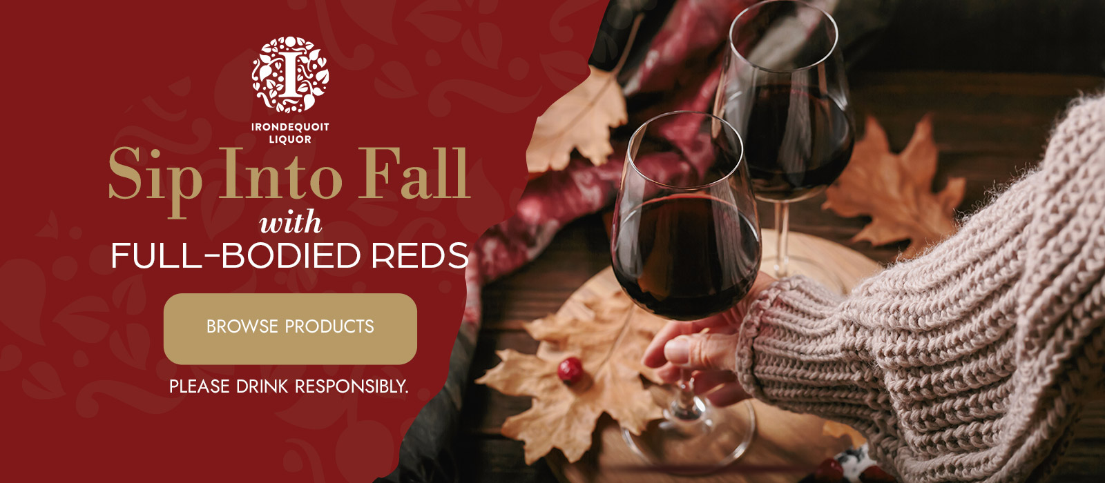 two hands clinking red wine glasses on a table with autumn leaves and cozy sweaters